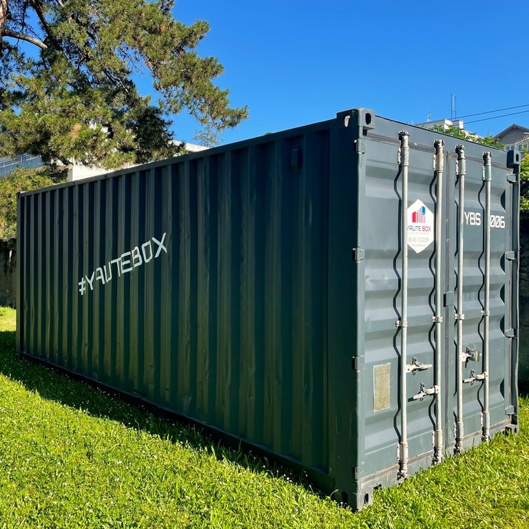 Container 20 pieds en location dans un parc sur pelouse verte et container gris fonce
