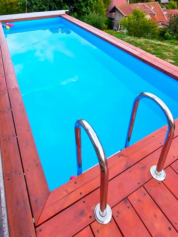Bassin de piscine bleu entouré d'une margelle en bois type douglas de la societe yaute box