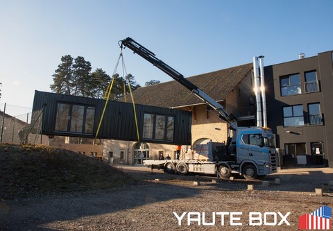container ecole en cour d'installation soulevé par camion grue gris clair et bleu