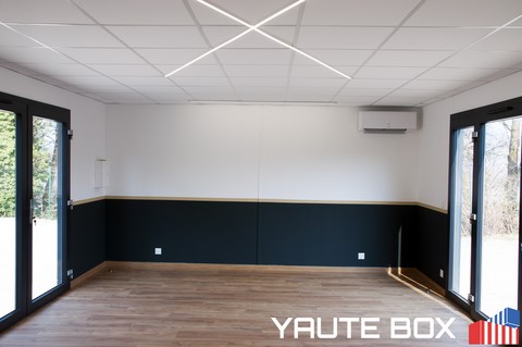 interieur du container ecole parquet bois stratifié mur blanc avec soubassement noir et liseré or