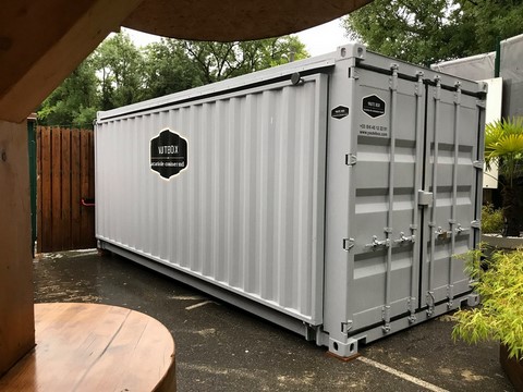 container stand evnementiel fermé gris clair dans une cour de restaurant